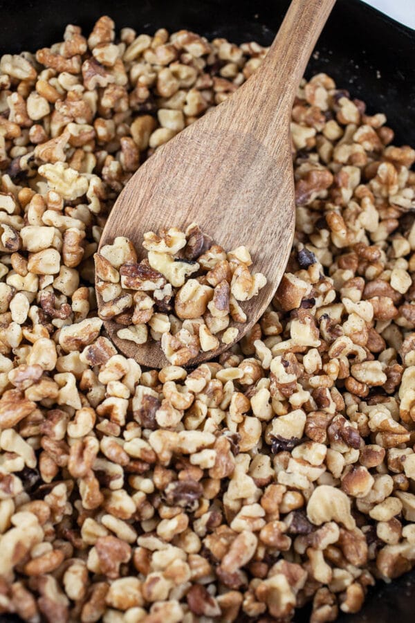 This Maple Bourbon Walnut Pie puts a twist on the traditional pecan pie. It's sweetened with maple syrup and kicked up with a shot of bourbon. This homemade pie is one of my favorite dessert recipes. I will take this maple bourbon walnut pie over pecan any day! #pie #maple #bourbon #walnut #thanksgiving Toasted walnuts in small cast iron skillet.