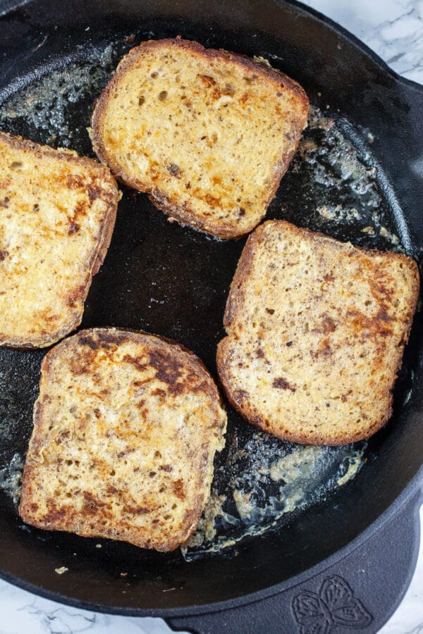 Cooked bread slices in black cast iron skillet.