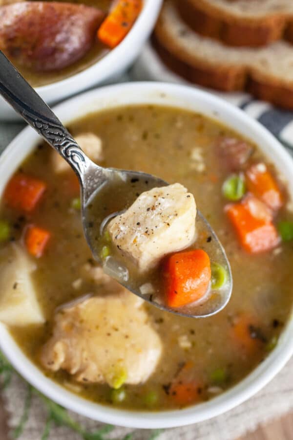 Spoonful of gluten free chicken stew lifted from white bowl.