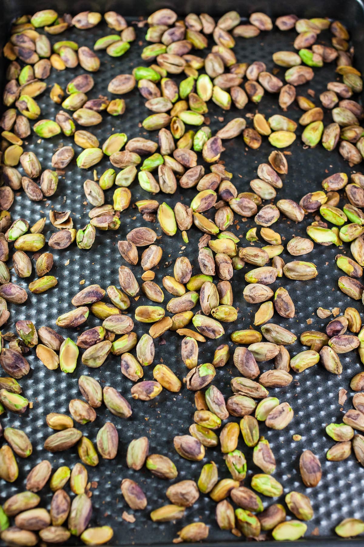 Roasted pistachios on baking sheet.