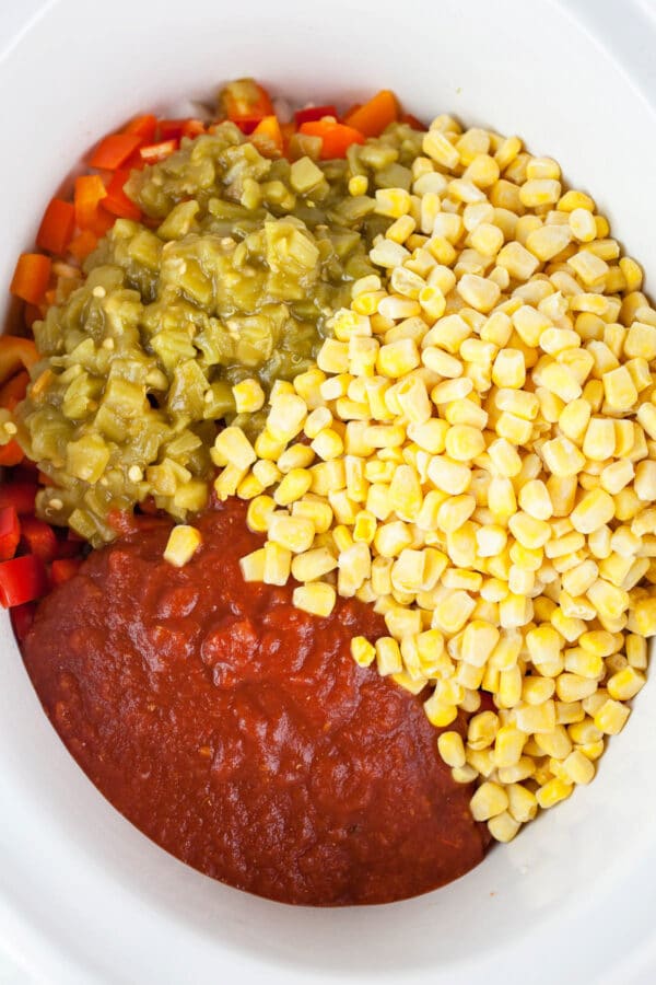 Corn, green chilis, and crushed tomatoes in white slow cooker.