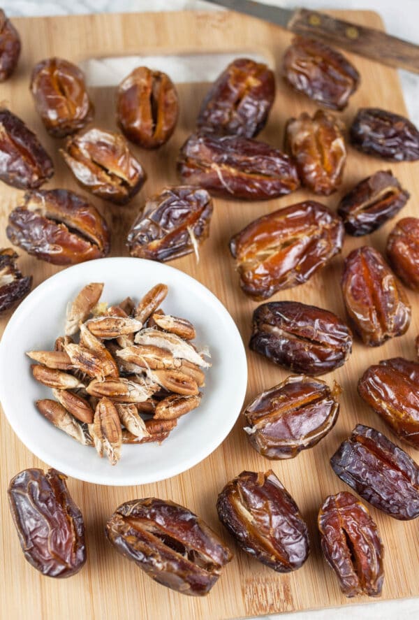 Pitted Medjool dates on wooden cutting board.