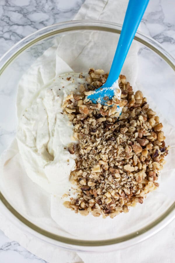 Chopped walnuts and whipped feta in glass bowl.