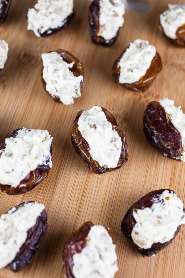 Whipped feta stuffed into Medjool dates on wooden cutting board.