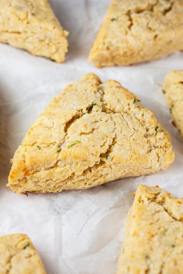 Baked cheddar chives scones on white surface.