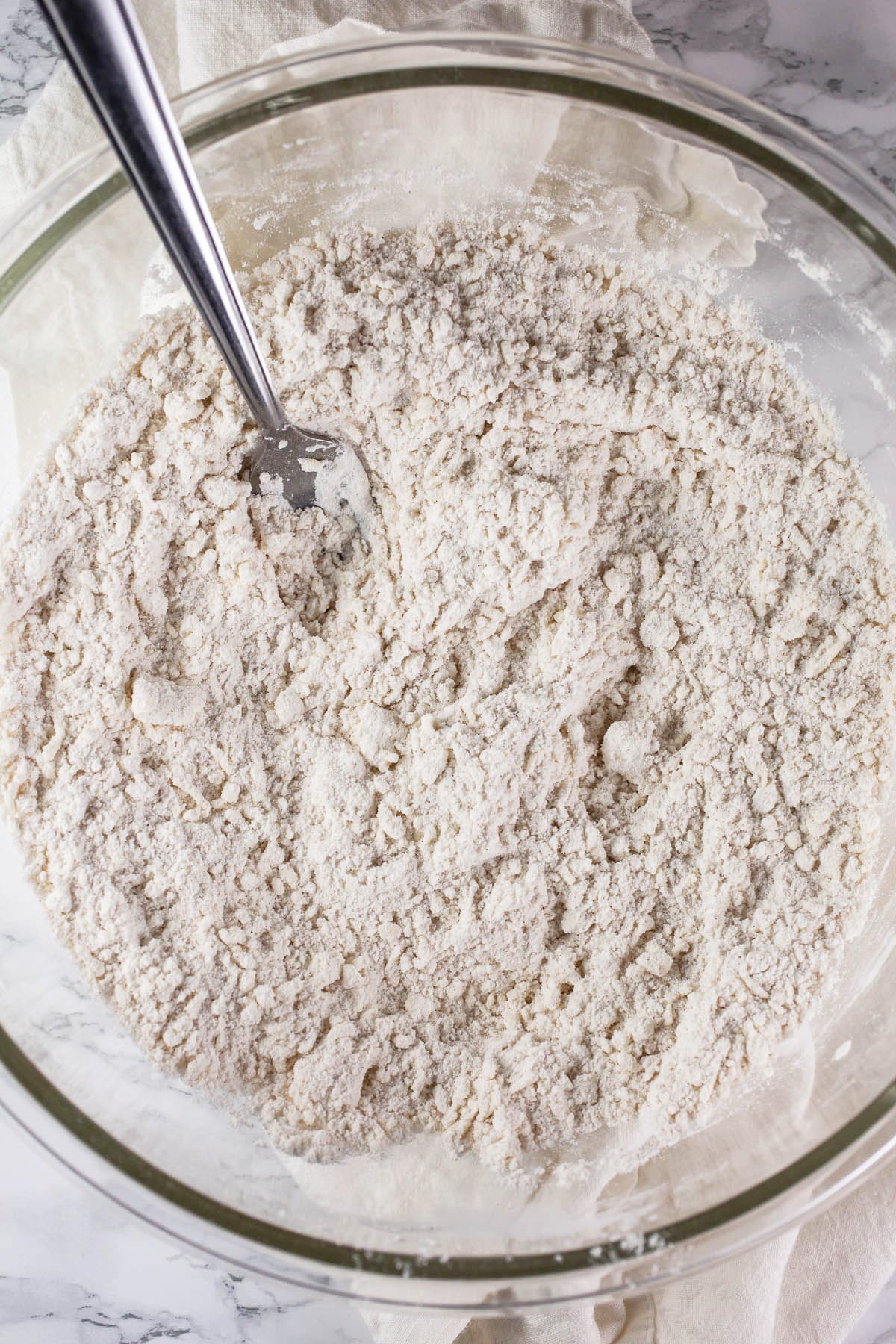 Butter and dry ingredients combined in glass bowl.