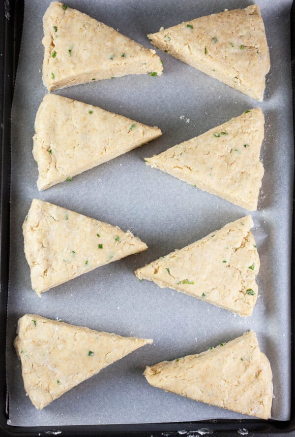 Unbaked cheese scones on parchment paper lined baking sheet.