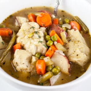 Gluten free Dutch oven vegetable stew with dumplings in small white bowl.