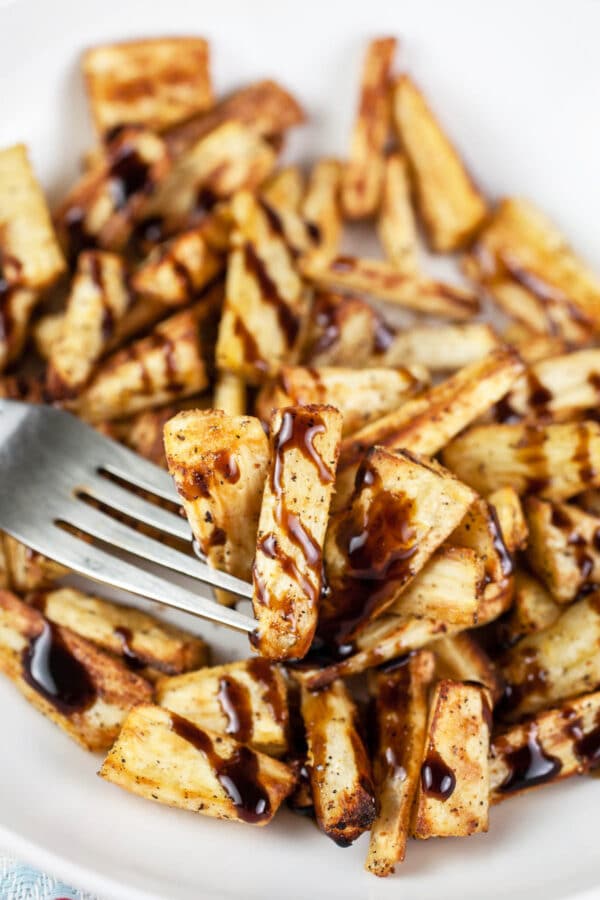 Air fryer parsnips with balsamic glaze in white bowl with fork.