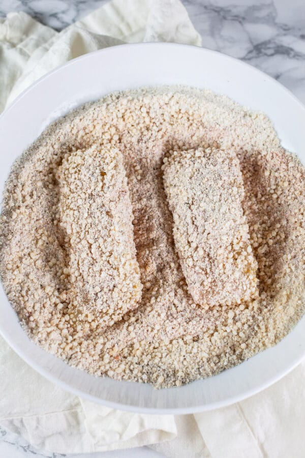 Walleye fillets coated in spiced breadcrumb mixture in white bowl.
