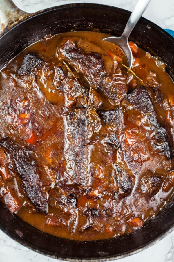 Cooked short ribs with sauce in cast iron Dutch oven.