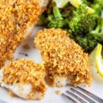 Panko baked cod with breadcrumb topping on white plate with broccoli.