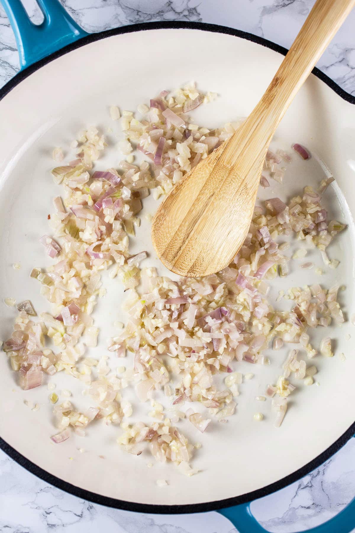 Garlic and shallots sautéed in white cast iron skillet.