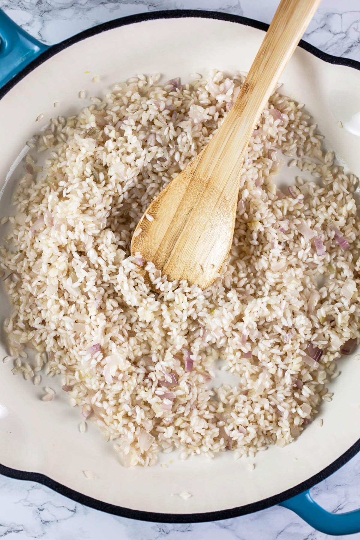 Garlic, shallots, and Arborio rice sautéed in white cast iron skillet.
