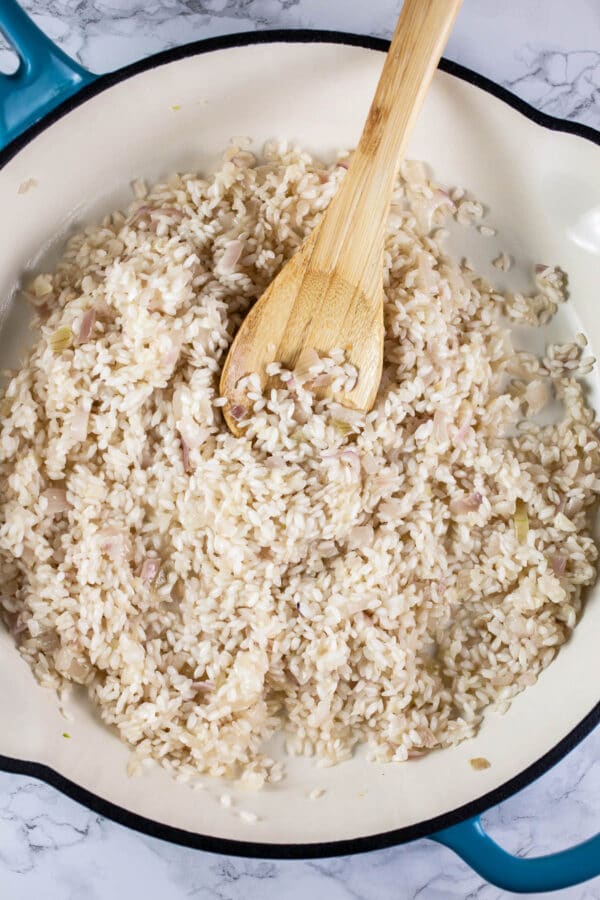 Garlic, shallots, Arborio rice, and white wine sautéed in white cast iron skillet.