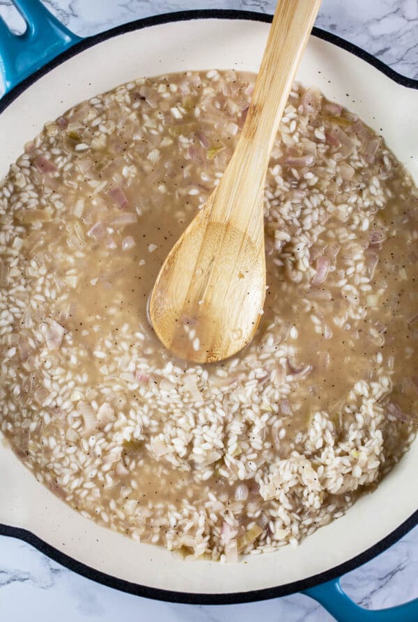 Chicken broth and Arborio rice in white cast iron skillet.