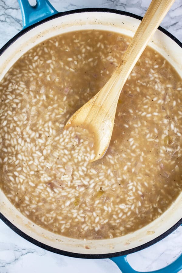 Arborio rice and chicken stock in white cast iron skillet.