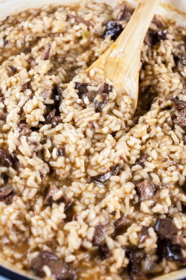 Short rib risotto in skillet with wooden spoon.