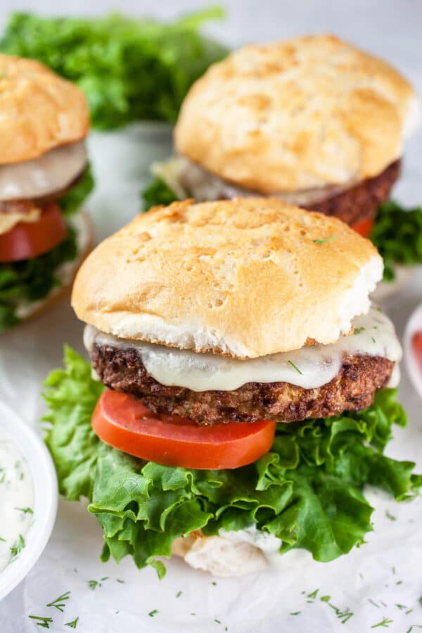 Turkey burgers on buns with lettuce, tomatoes, and dill aioli.