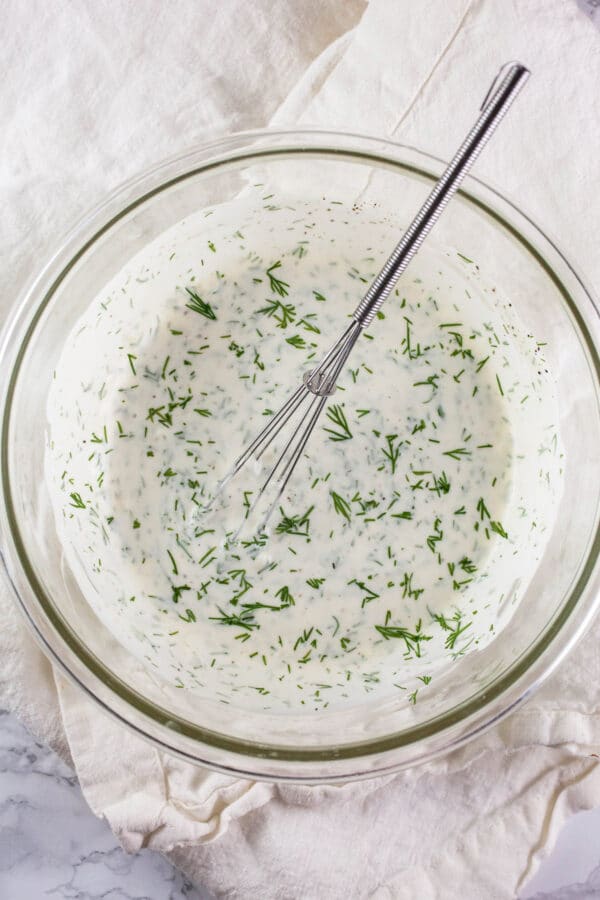 Lemon garlic dill aioli in small glass bowl with whisk.