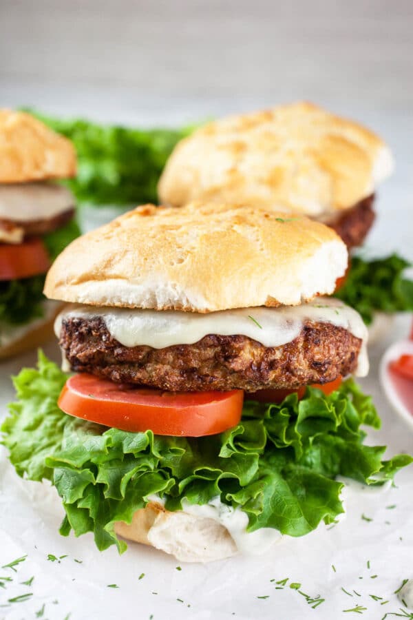 Air fryer turkey burgers on buns with lettuce, tomato, and dill aioli.
