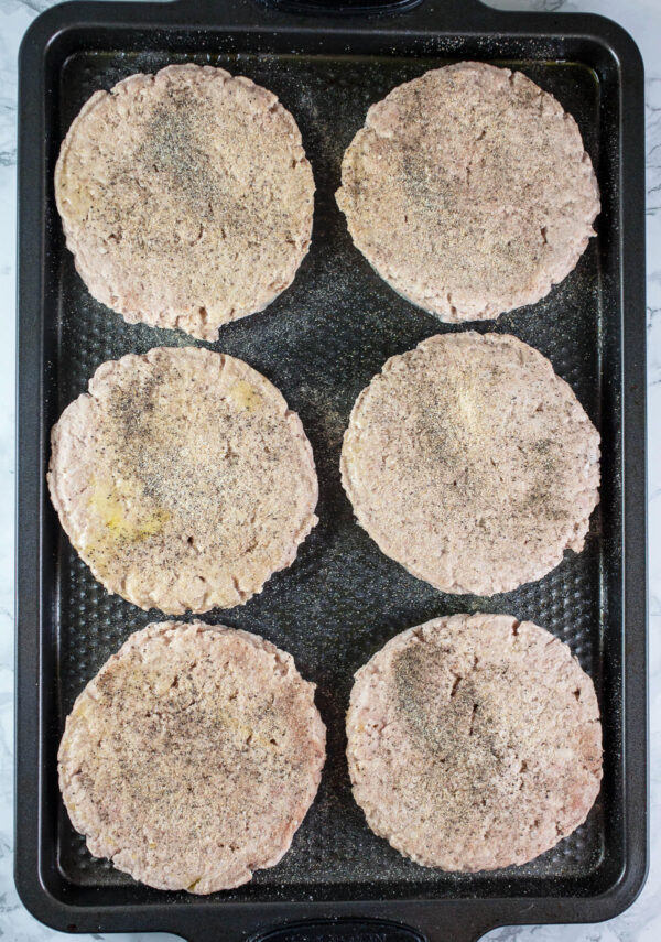 Frozen turkey burger patties on metal baking sheet.