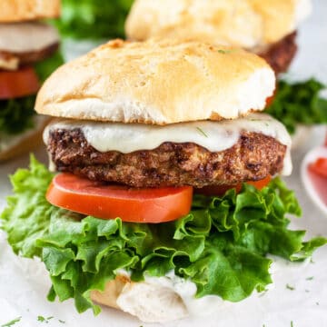 Air fryer turkey burgers on buns with lettuce, tomato, and dill aioli.