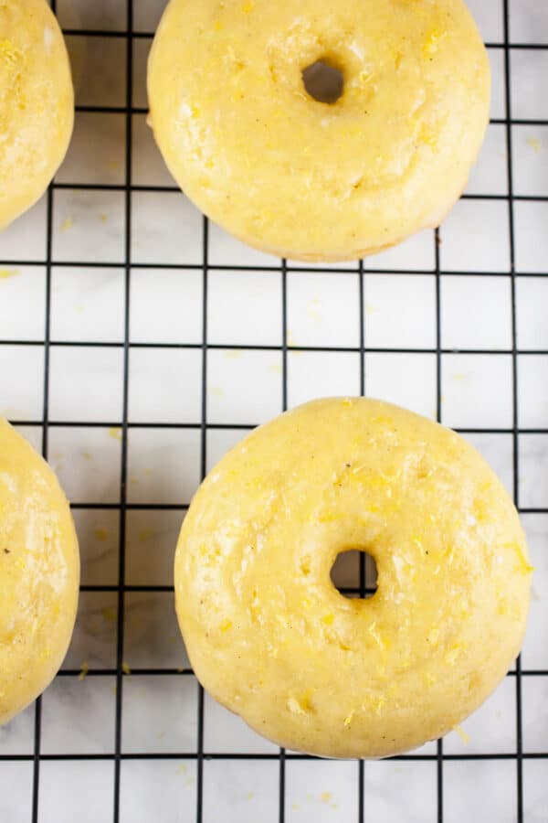 Glazed lemon doughnuts on cooling rack.