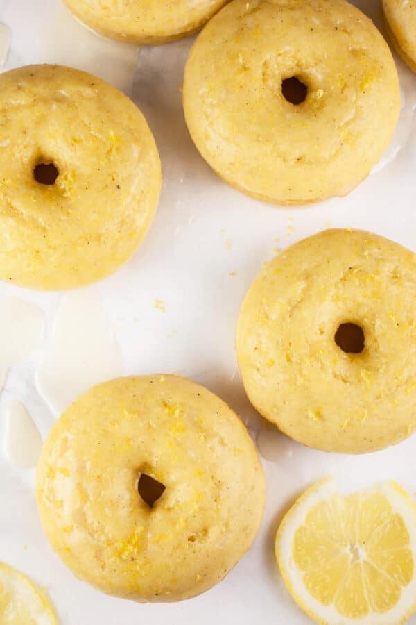 Lemon doughnuts with lemon slices on white surface.