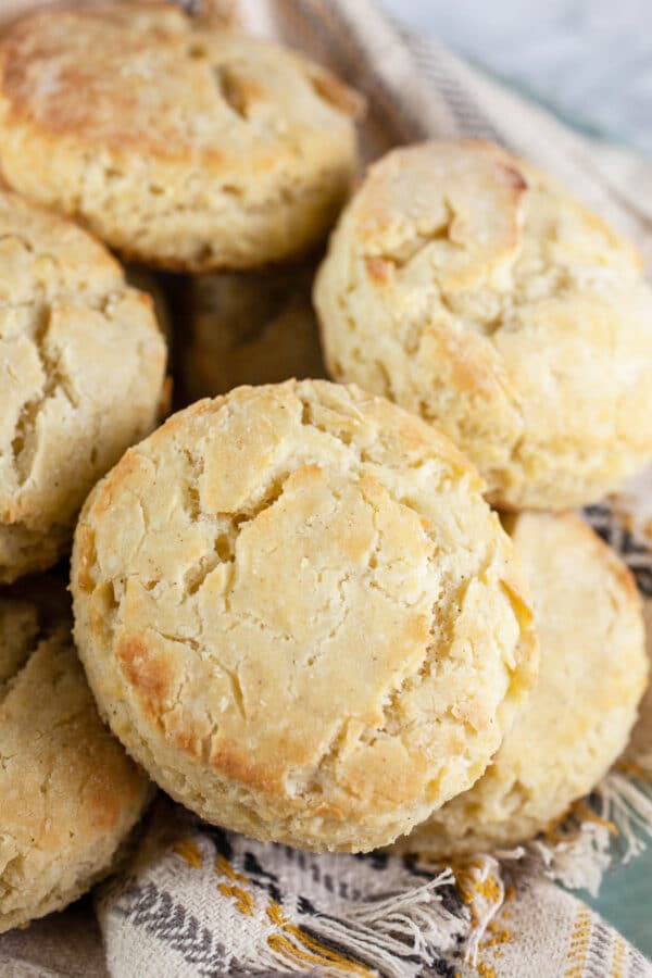 Learn How To Make Gluten Free Biscuits that are light, buttery, and flaky! These step by step instructions make the process easy. This recipe uses Bob's Red Mill 1 to 1 flour and buttermilk for a great old fashioned rustic biscuit. There is nothing better than homemade biscuits made from scratch. Perfect for breakfast or as a side for holiday dinners like Easter or Thanksgiving! #biscuits #glutenfree Gluten free biscuits in bowl with towel.
