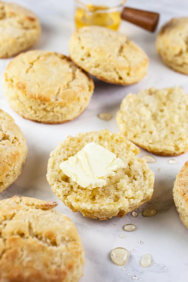 Gluten free biscuits with butter and honey on white surface.