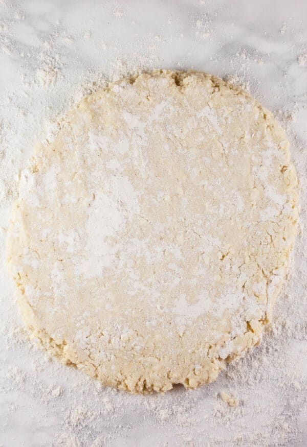 Biscuits dough formed into round on white surface.