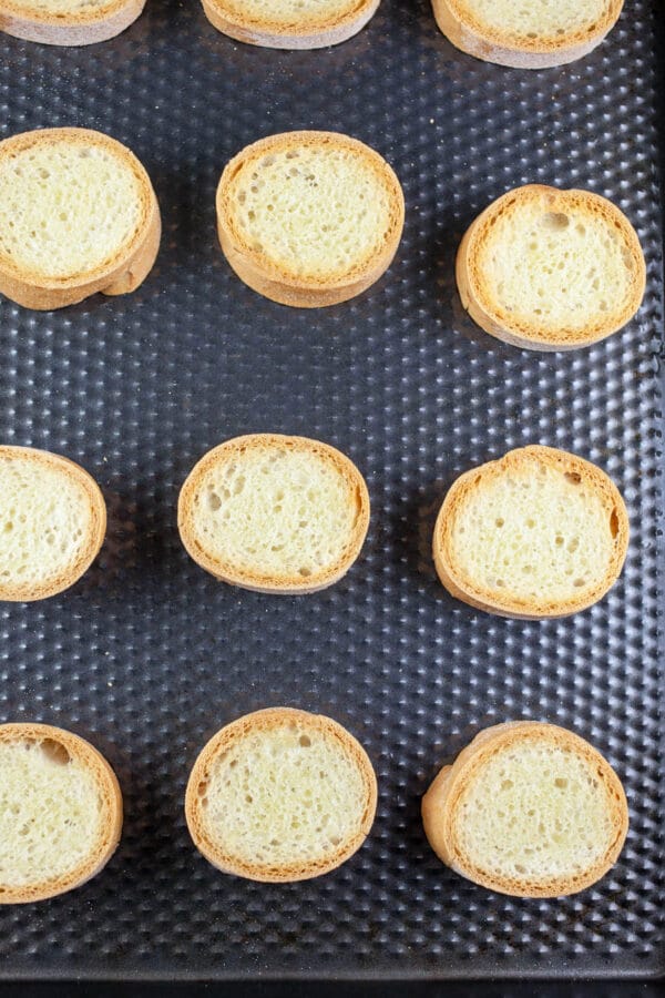 Toasted crostini on baking sheet.