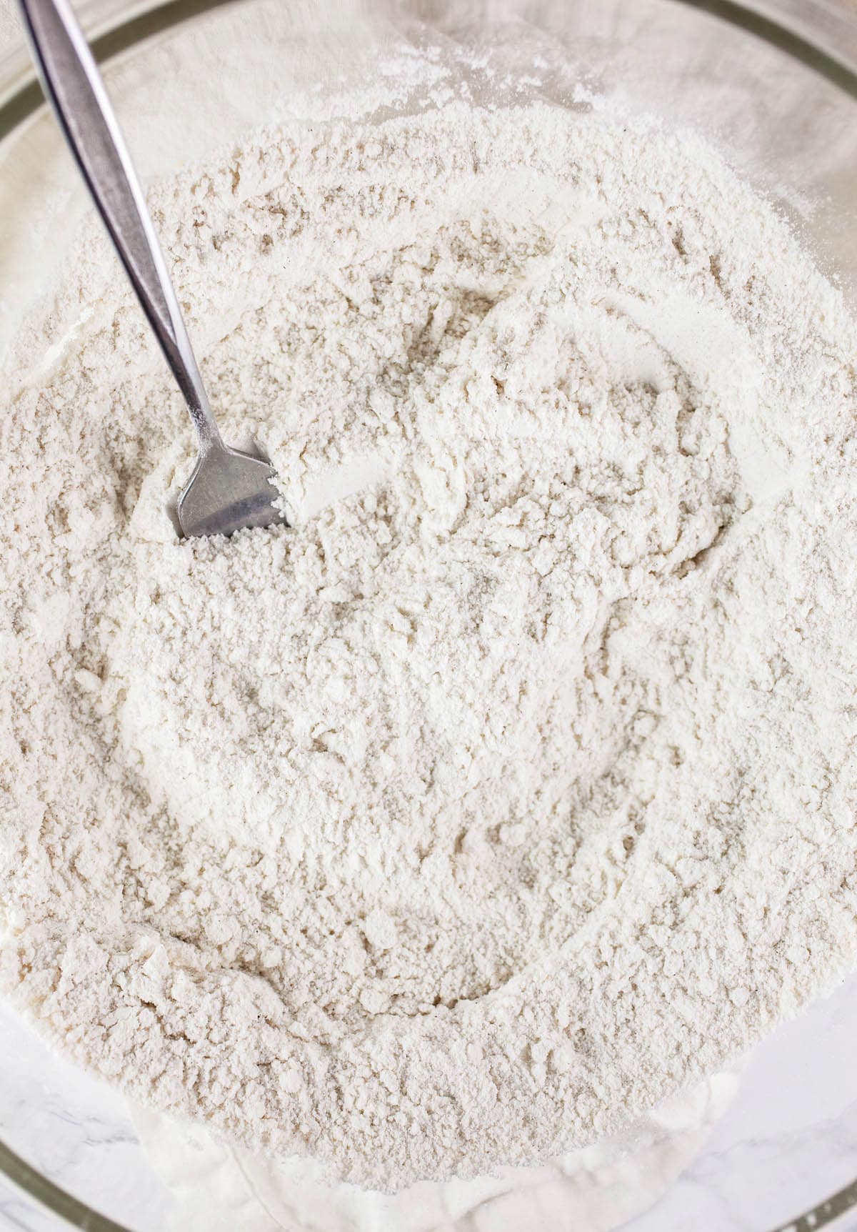 Dry ingredients in large glass mixing bowl with fork.