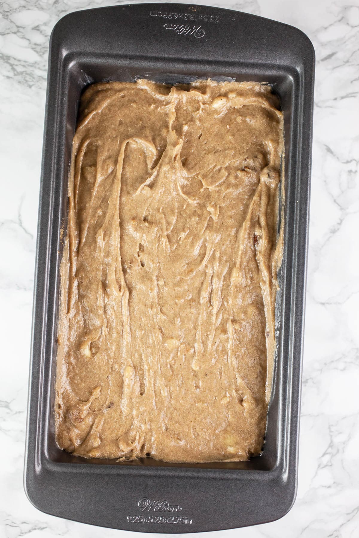 Unbaked banana bread batter in metal loaf pan.