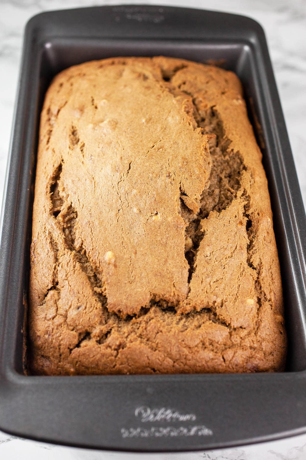 Baked banana bread in metal loaf pan.