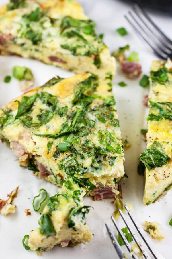 Slices of ham and cheese frittata with forks.