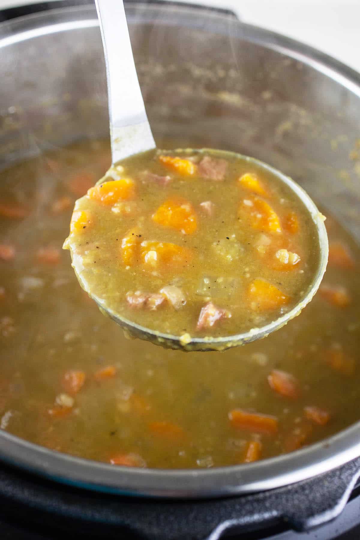 Scoop of split pea ham soup lifted from Instant Pot on metal ladle.