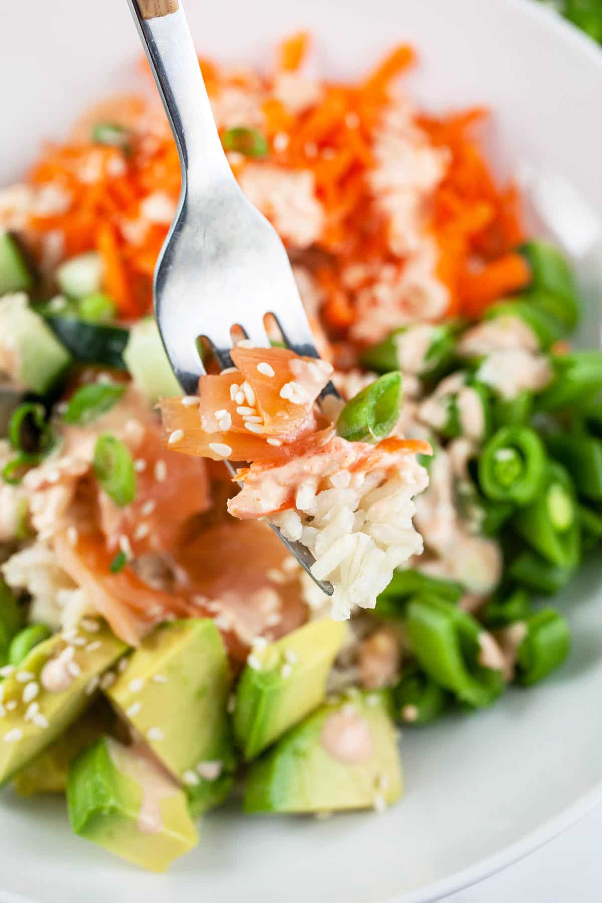 Forkful of smoked salmon and rice lifted from white bowl.