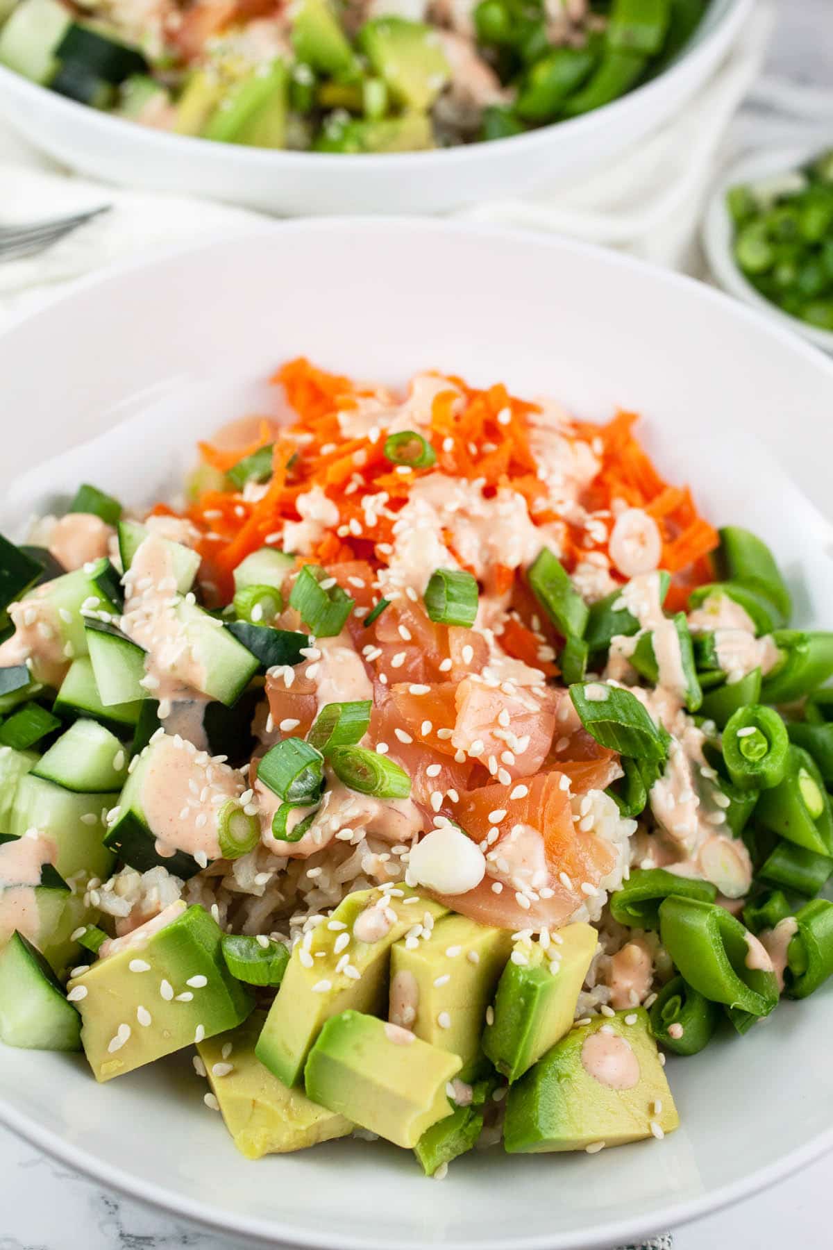 Smoked salmon rice bowl with spicy mayo, sesame seeds, and green onions.