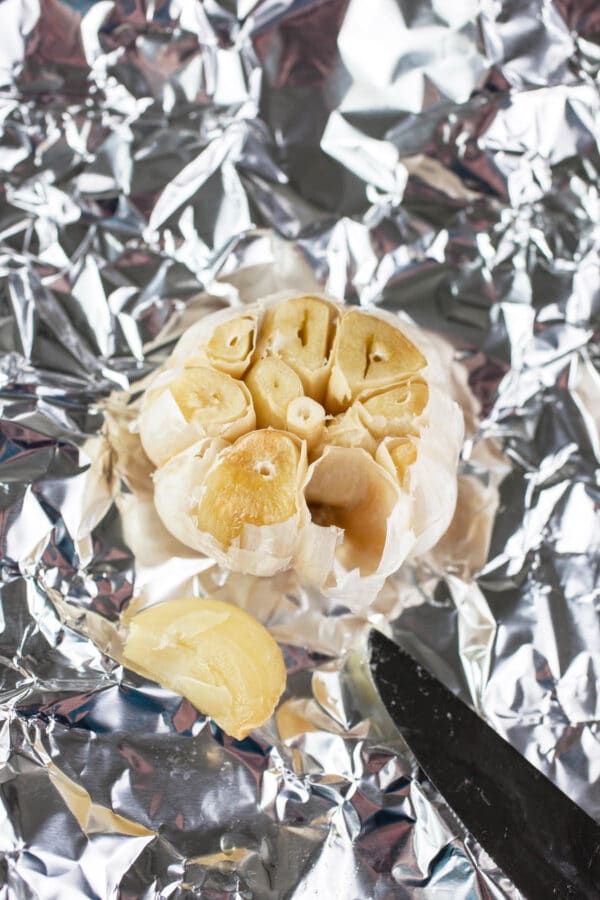 One clove of roasted garlic removed from garlic bulb on piece of tinfoil.