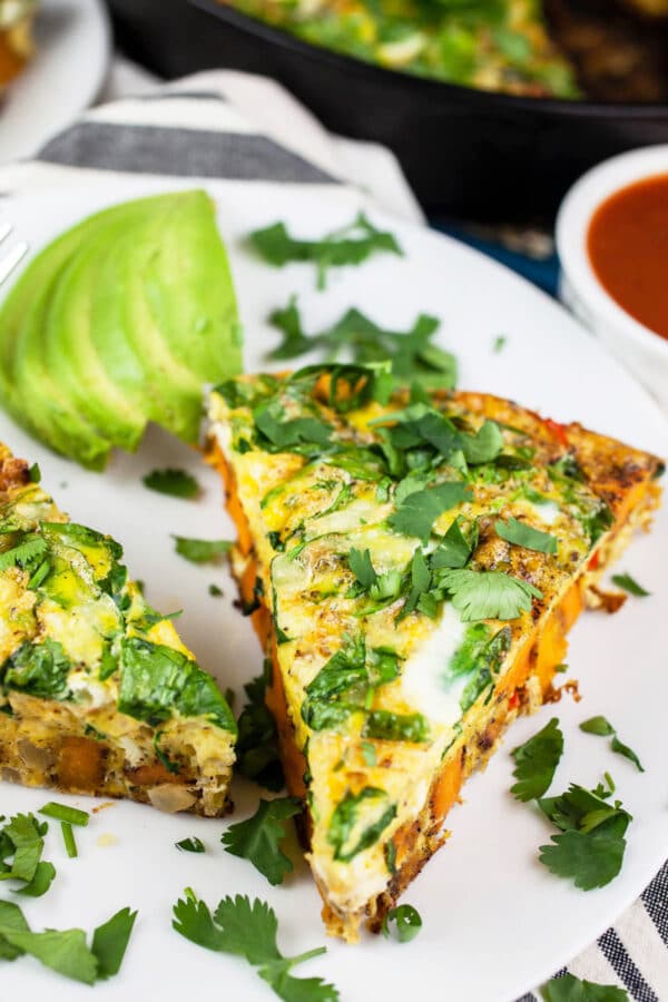 Southwest frittata with fresh cilantro and sliced avocado on white plate.