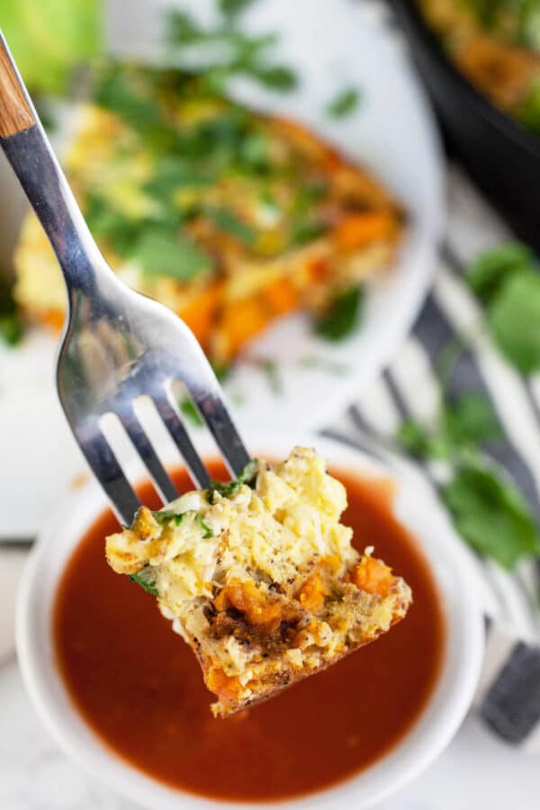 Forkful of Southwest frittata in front of small bowl of salsa.