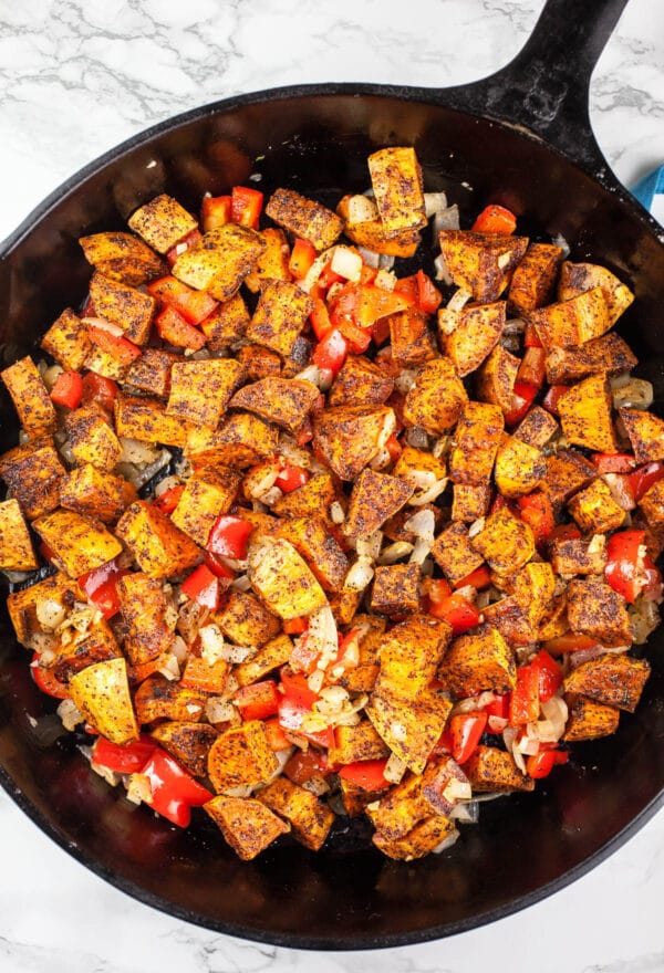 Sautéed red bell peppers and roasted sweet potatoes in cast iron skillet. 