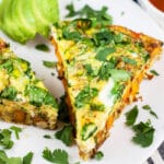 Southwest frittata with fresh cilantro and sliced avocado on white plate.