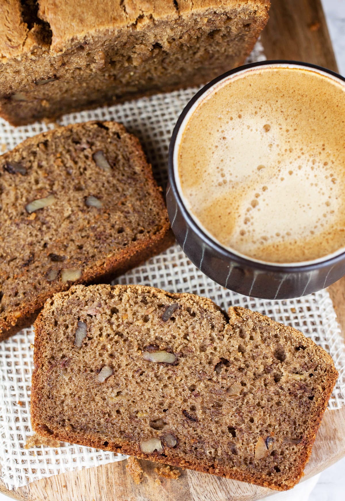 Banana bread on wooden board with cup of coffee.