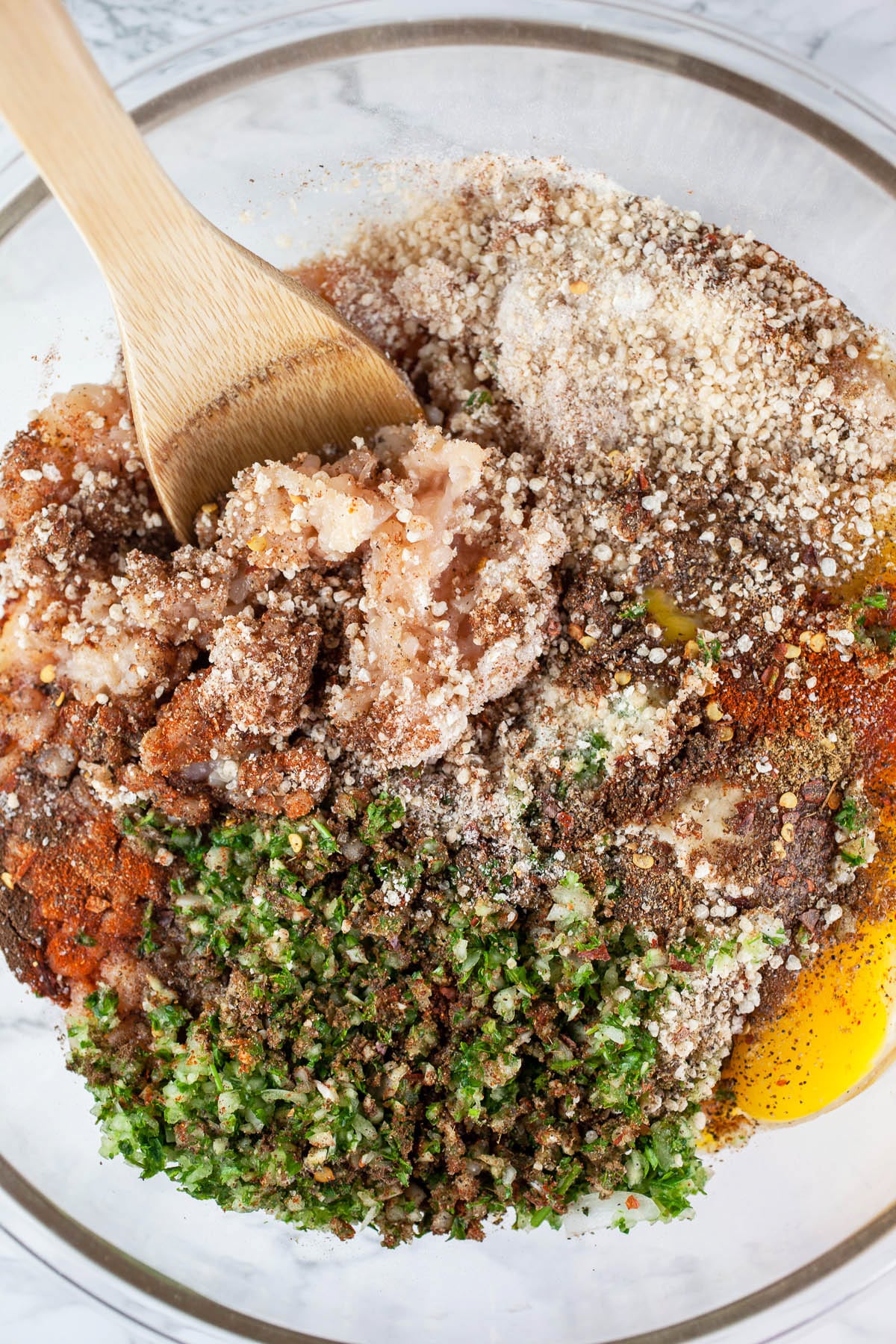 Ground chicken, herbs, spices, eggs, and Panko breadcrumbs in large glass mixing bowl.