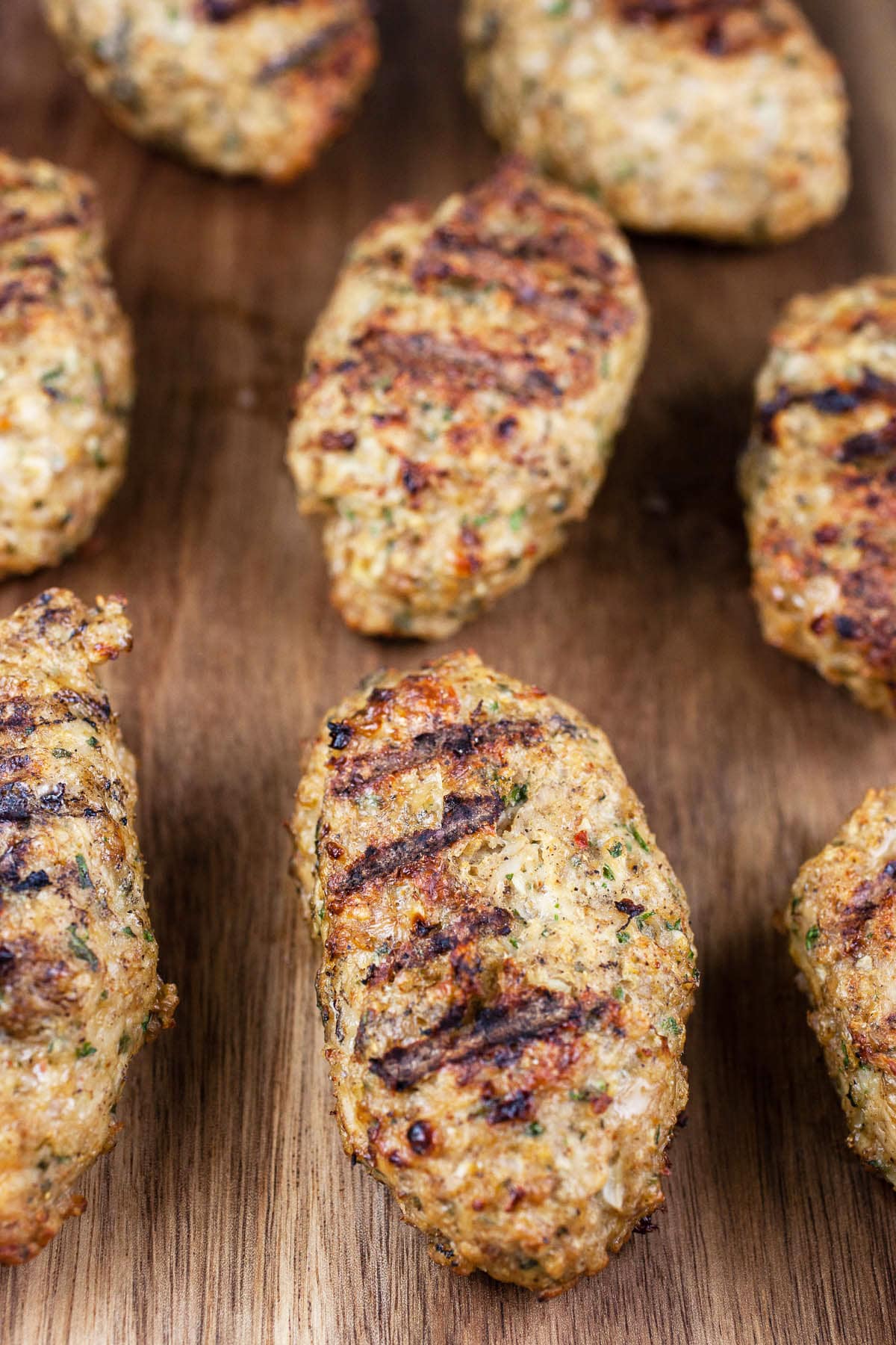 Grilled chicken kofta on wooden cutting board.