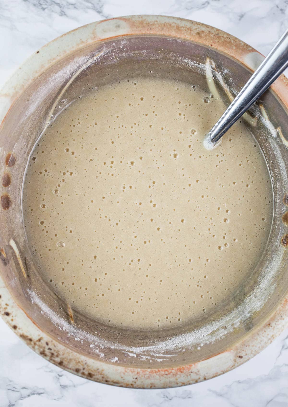 Wet cake ingredients mixed with flour in ceramic bowl.