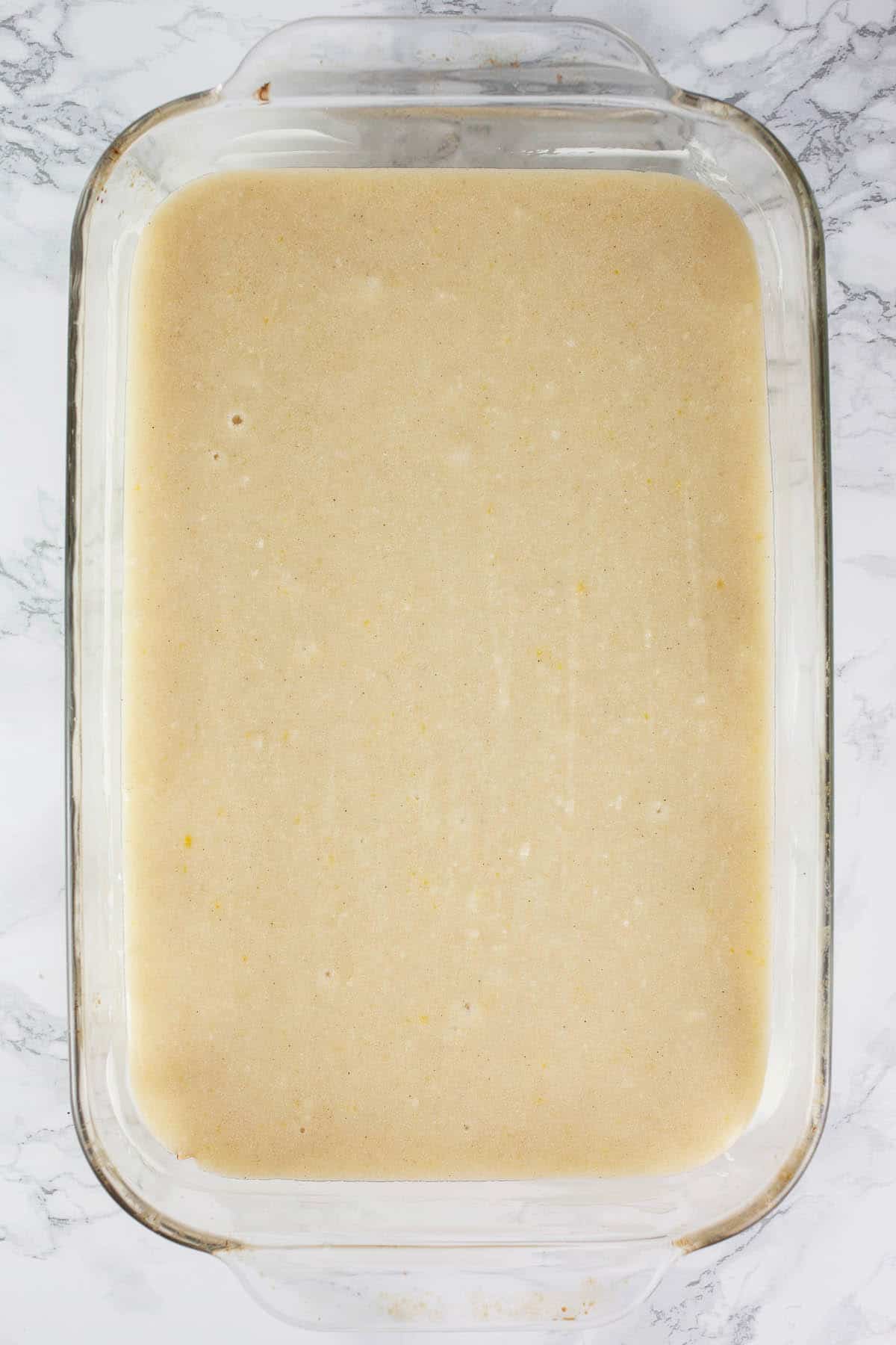 Almond cake batter in glass baking dish.